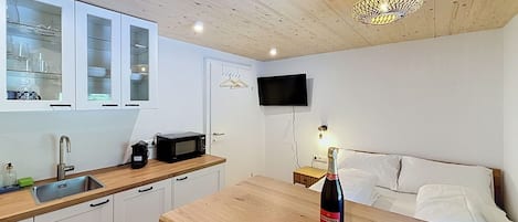 A compact kitchenette with a microwave, coffee maker, and a bottle of wine on the counter.