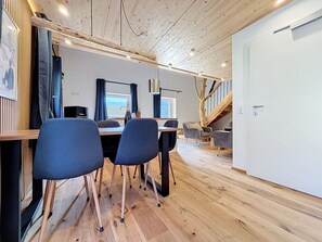 Ein modernes Interieur mit Holzboden, einer Essecke mit Stühlen, einem Schreibtisch und einer Treppe, die in ein Obergeschoss führt.