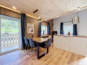 Et moderne køkken med en træbordplade, et spiseområde med bord og stole, og udsigt til en have gennem vinduet.