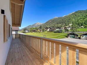 En træterrasse med udsigt over et bjerglandskab og et skilt til en lokal virksomhed.