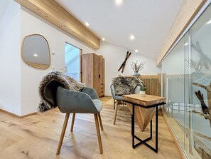 Et moderne interiør med træloft, et rundt spejl, en sofasofa betrukket med pels, et spisebord og en glasvæg.