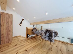 Ein Zimmer mit Holzboden, einem großen Spiegel, einem Holzschrank und einem Sessel mit Felldecke.