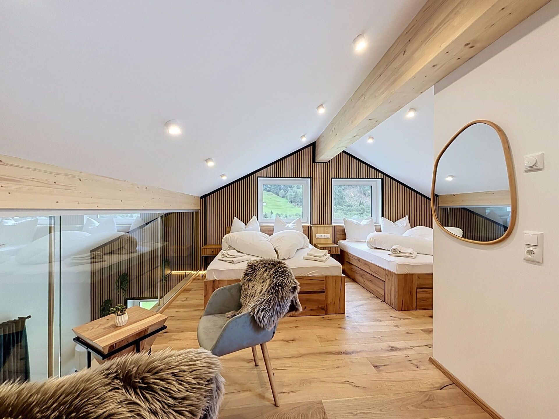 Un dormitori modern amb disseny d'estil loft, que inclou un llit, zona de seients i un gran mirall.