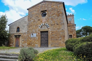 A historic stone building with a clock tower, a central arched entrance, and a bell tower. - Nice apartment for 2 people with A/C, WIFI, TV and panoramic view, close to San Gimignano (Castelfalfi)