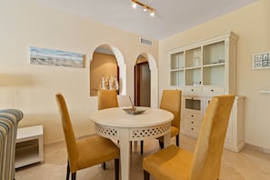 A dining area with a round table, four chairs, and a cabinet with glass doors. - RDR586 - Tropical 2-Bed Apartment with Pool Views (Estepona)
