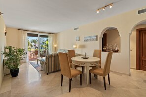 A dining area with a round table, chairs, and a view of the outdoors. - RDR586 - Tropical 2-Bed Apartment with Pool Views (Estepona)