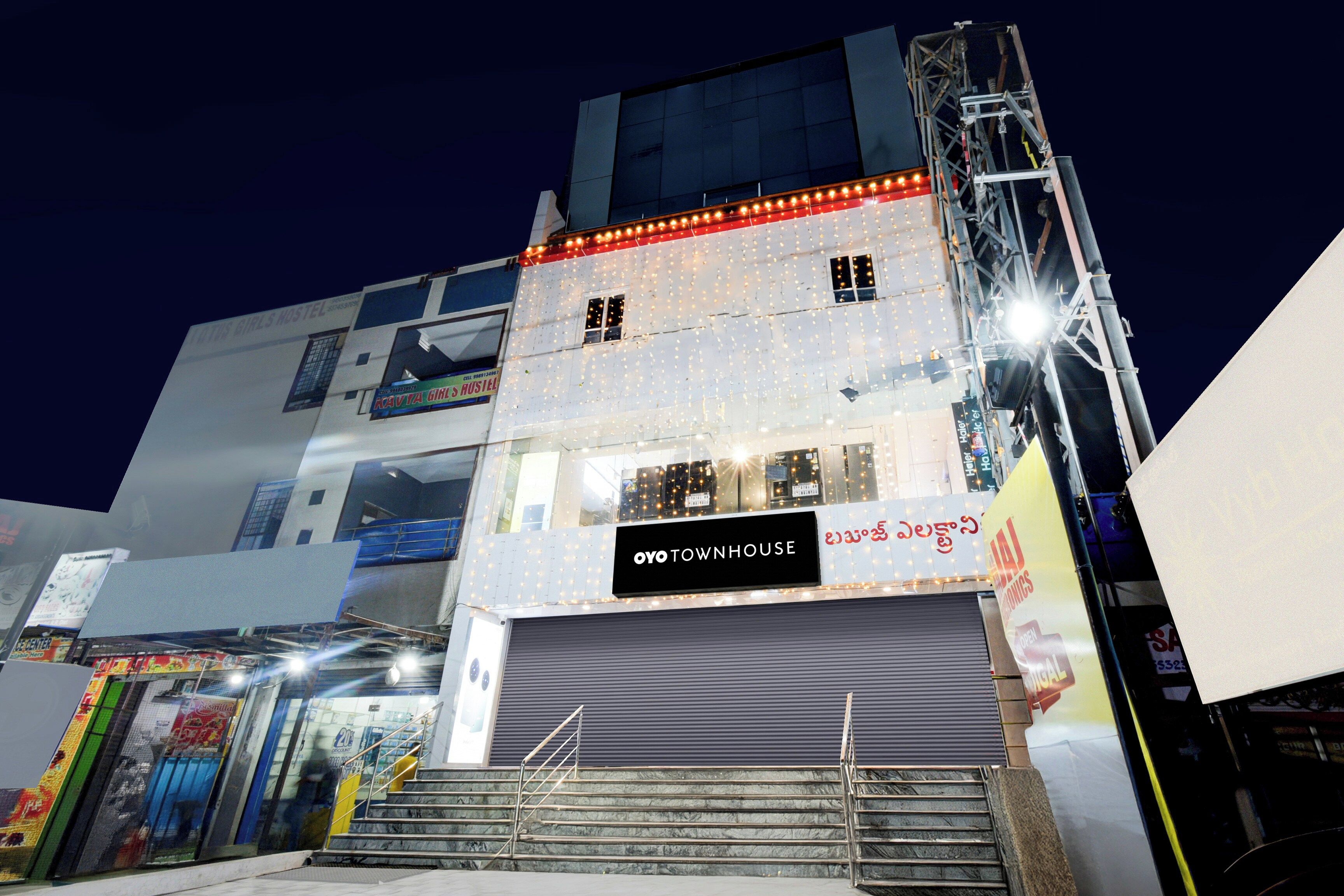 A multi-story building with a closed shop on the ground floor, a staircase leading to the upper floors, and a sign indicating 'OYO TOWNHOUSE'.