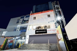Un immeuble à plusieurs étages, avec un commerce fermé au rez-de-chaussée, un escalier menant aux étages supérieurs et une enseigne indiquant « OYO TOWNHOUSE ».