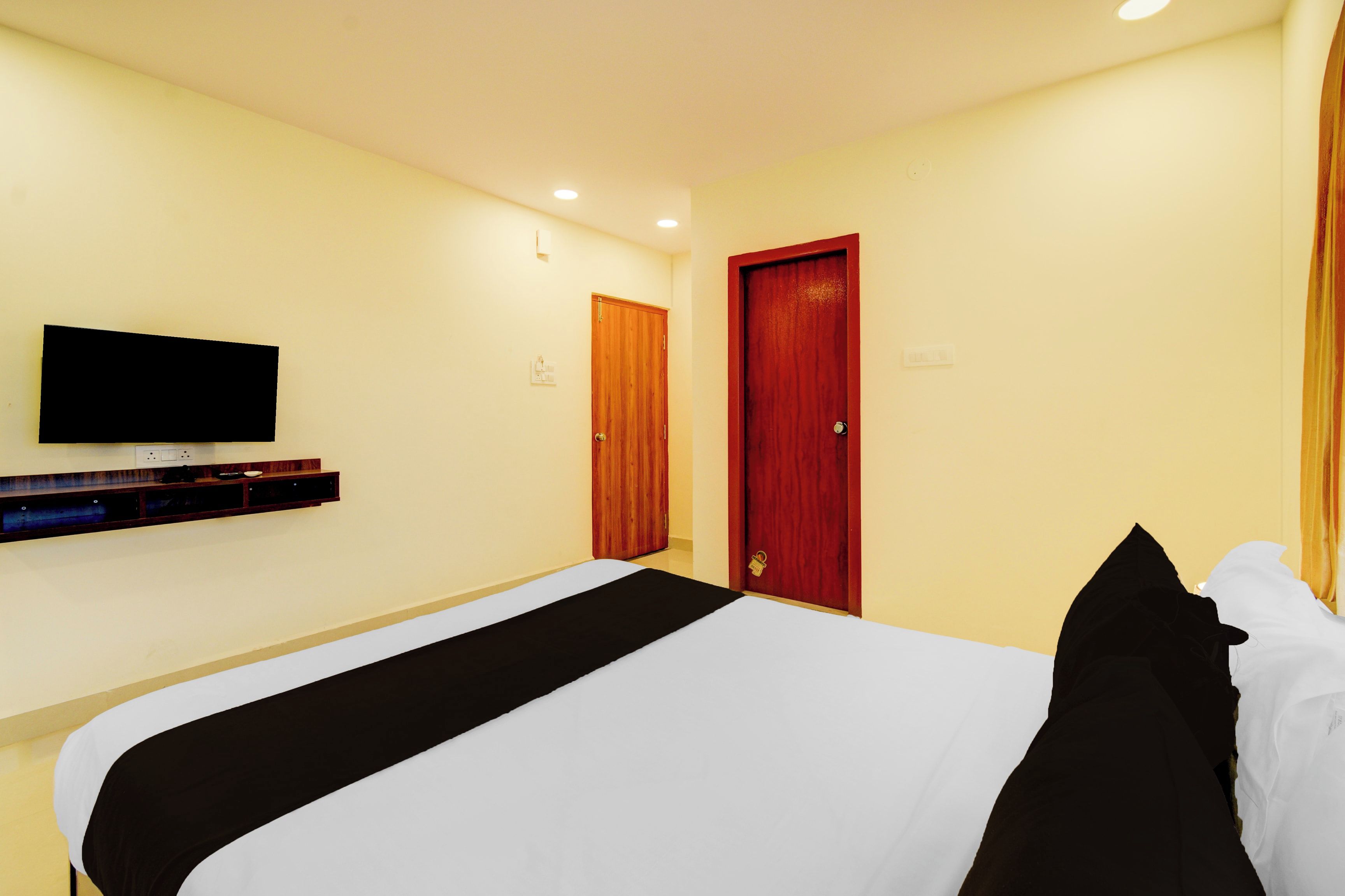A hotel room with a bed, a television mounted on the wall, and a door.