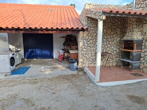 A residential property with a tiled roof, a stone wall, a laundry area, and a barbecue grill.