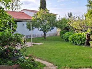 A well-maintained garden with a pathway leading to a white building with a red roof.