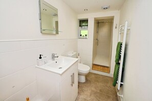 A modern bathroom with a white sink, toilet, and shower. - Susans Cottage (Horncastle)