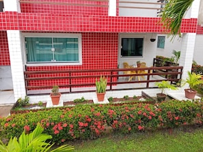 A building with a red-tiled facade, a wooden balcony, and potted plants. - Vacation Home in Itamaracá — Close to the Sea! (Ilha de Itamaracá)