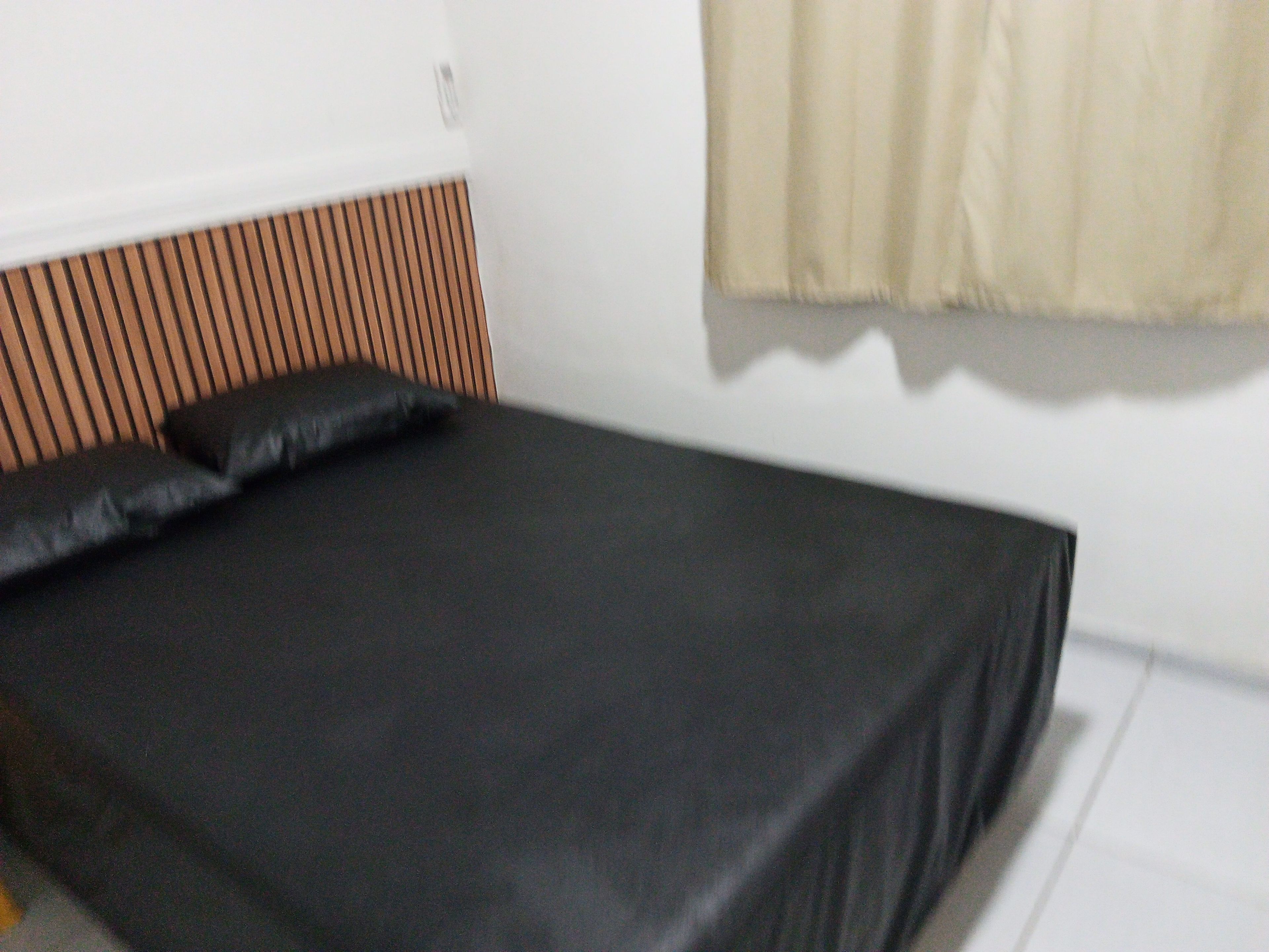 Una cama con colchón negro y cabecera de madera.