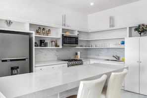 Una cocina moderna con una isla central, electrodomésticos de acero inoxidable y armarios blancos.