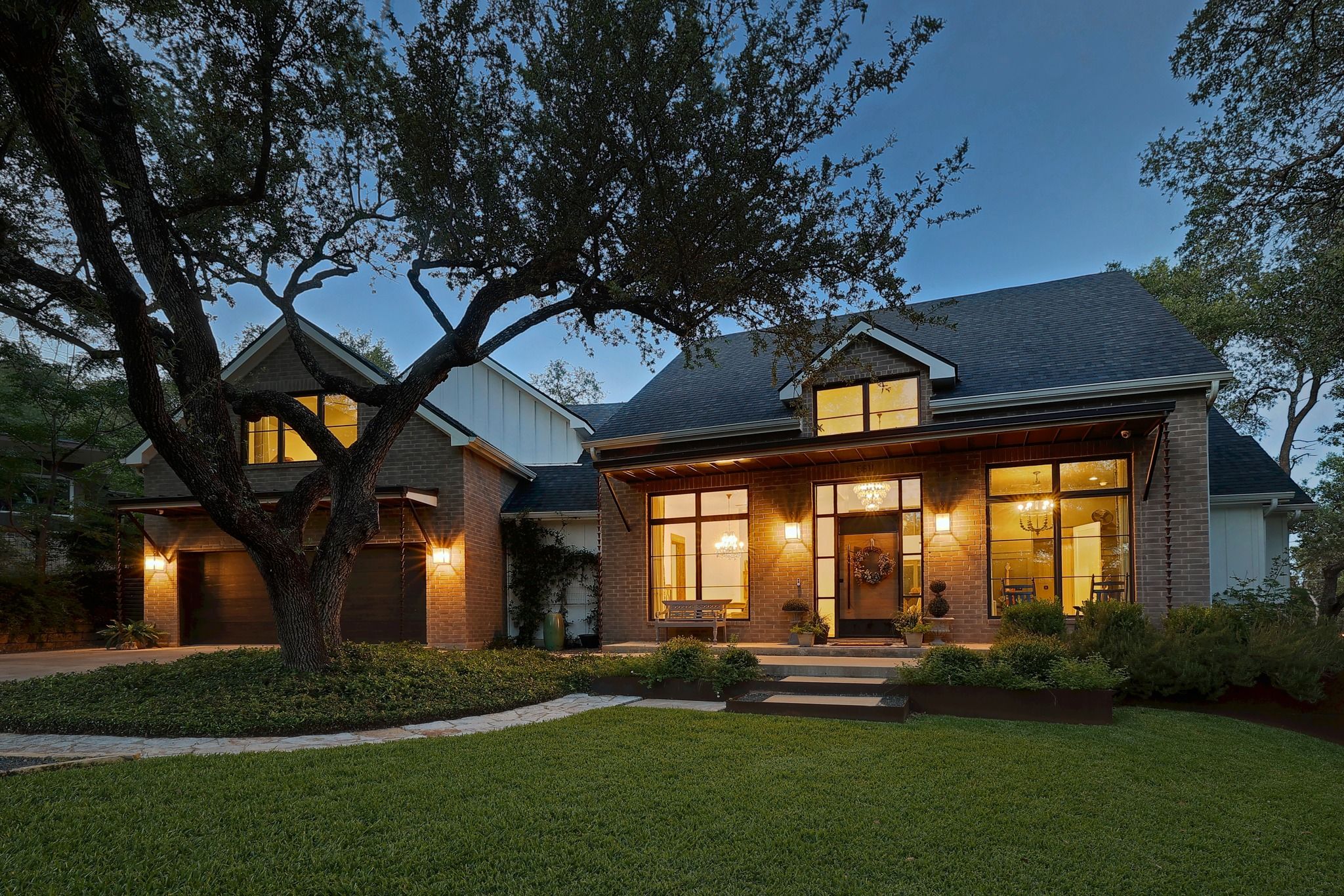 A two-story house with a well-maintained lawn and a large tree in the front yard.
