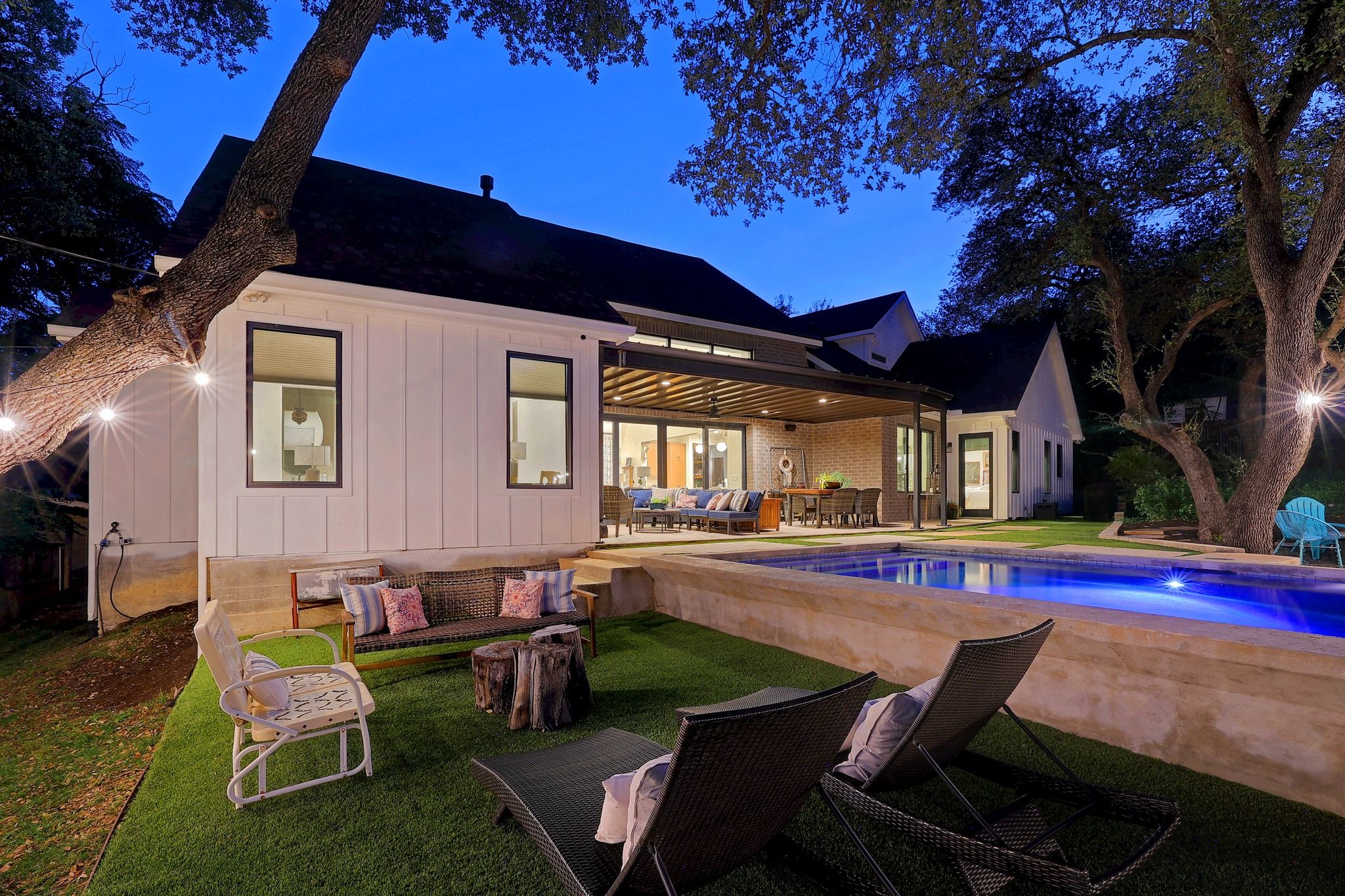 A modern house with a covered patio, outdoor seating, and a swimming pool.