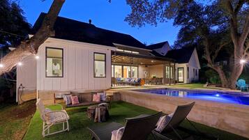 A modern house with a covered patio, outdoor seating, and a swimming pool.