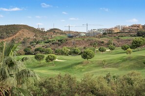 A golf course with a view of residential buildings and a hill in the background.