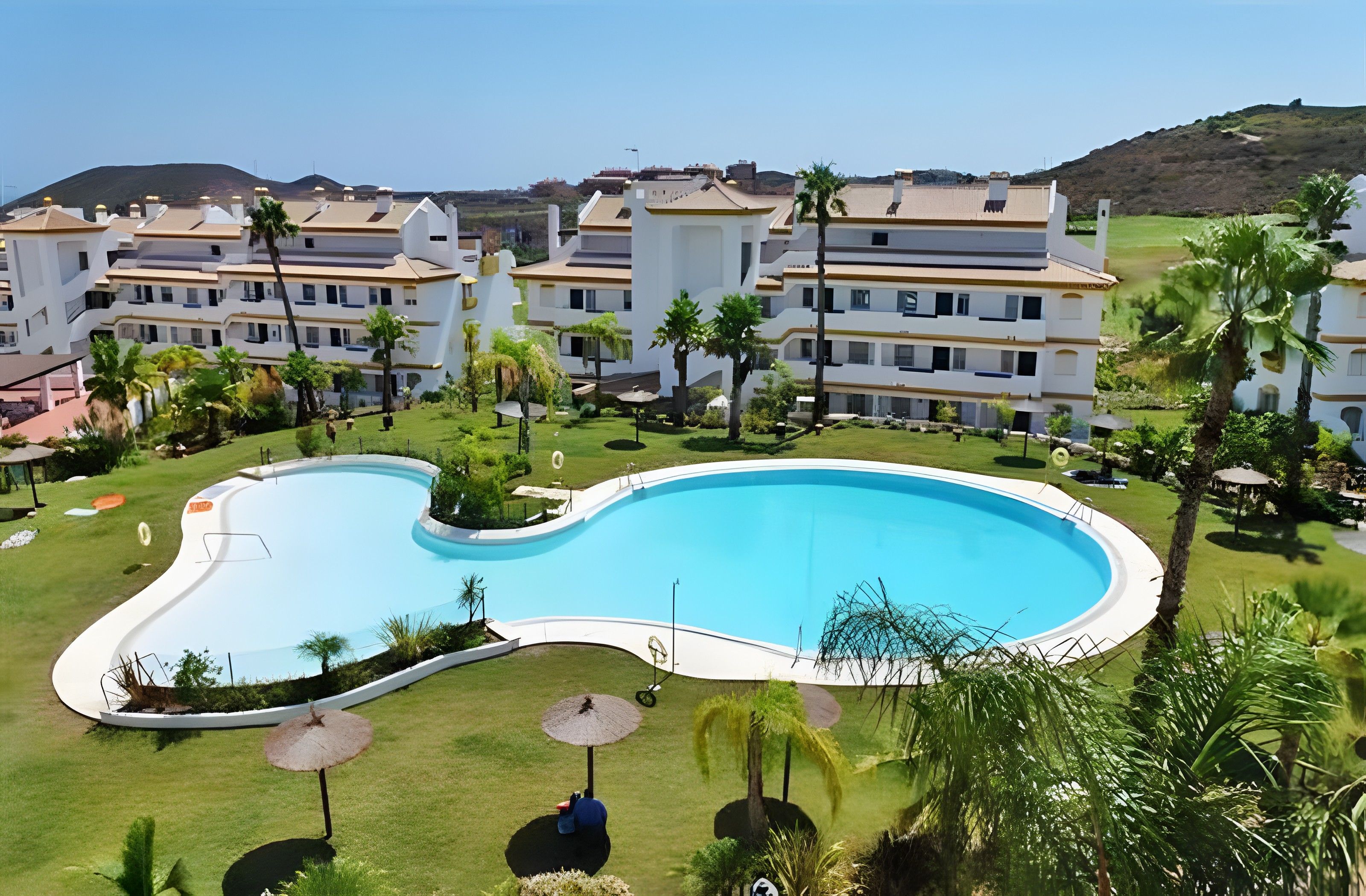 Un hôtel moderne doté d’une grande piscine, de nombreux balcons et d’un aménagement paysager luxuriant.