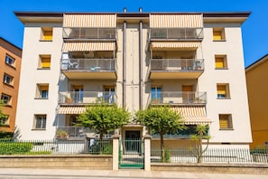 Un edificio residenziale a più piani con balconi, un cancello e un cielo sereno.