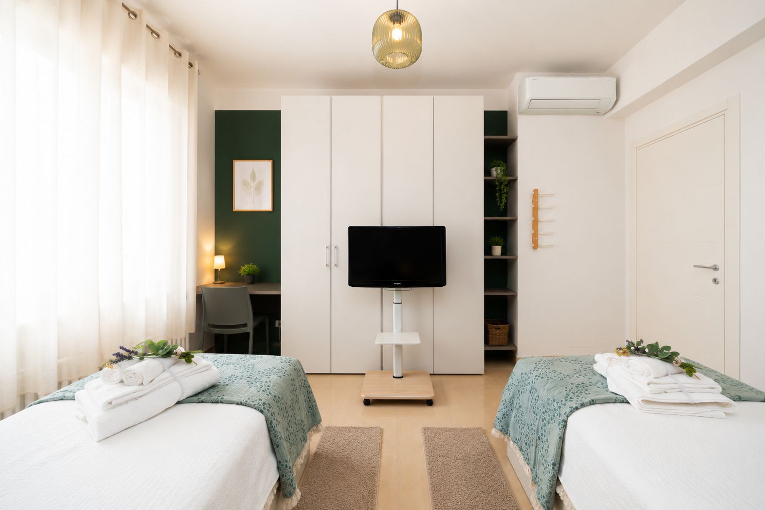 A hotel room with two beds, a desk, a television, and a wardrobe.