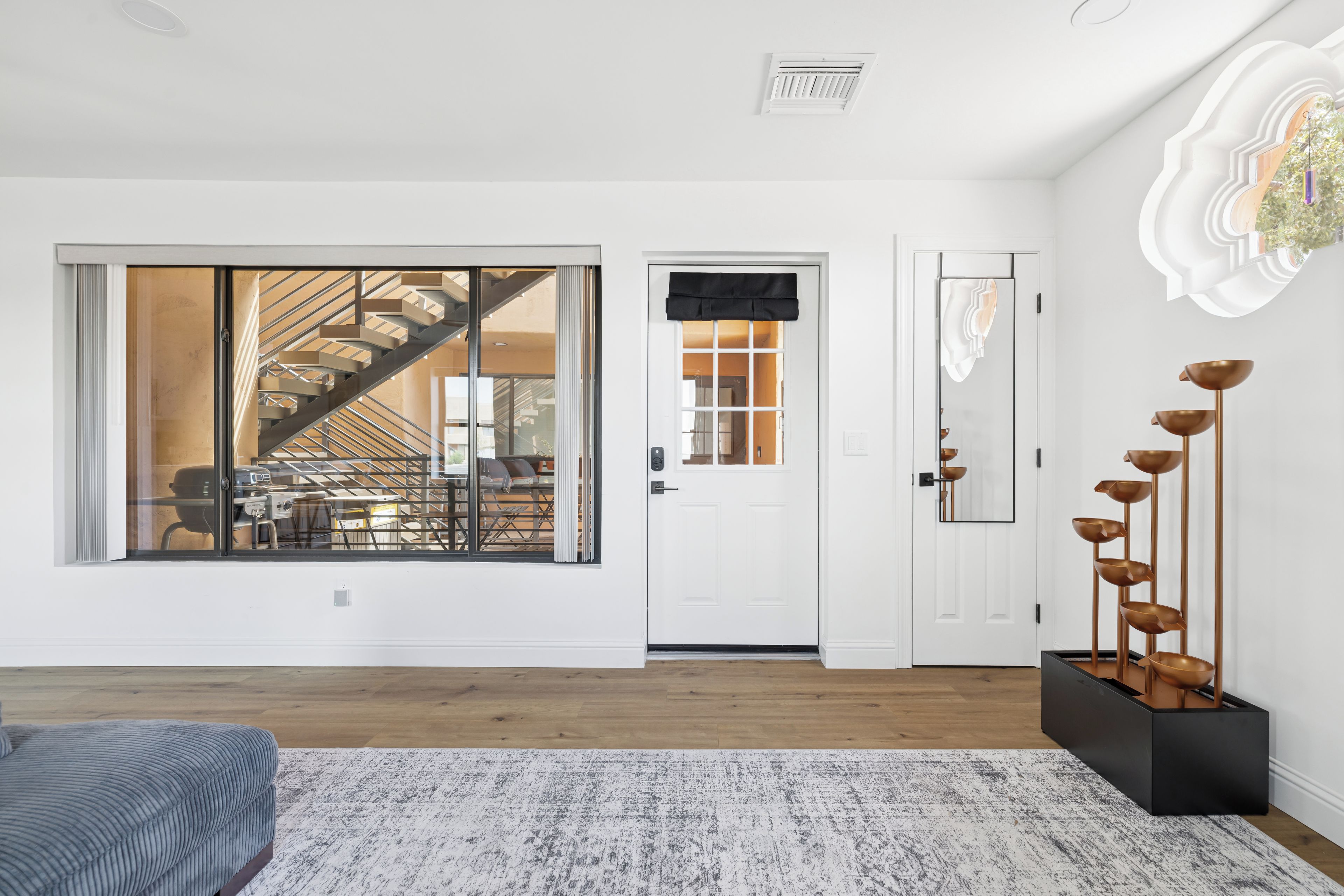 A modern interior with a large sliding glass door, a staircase, and a minimalist decor.