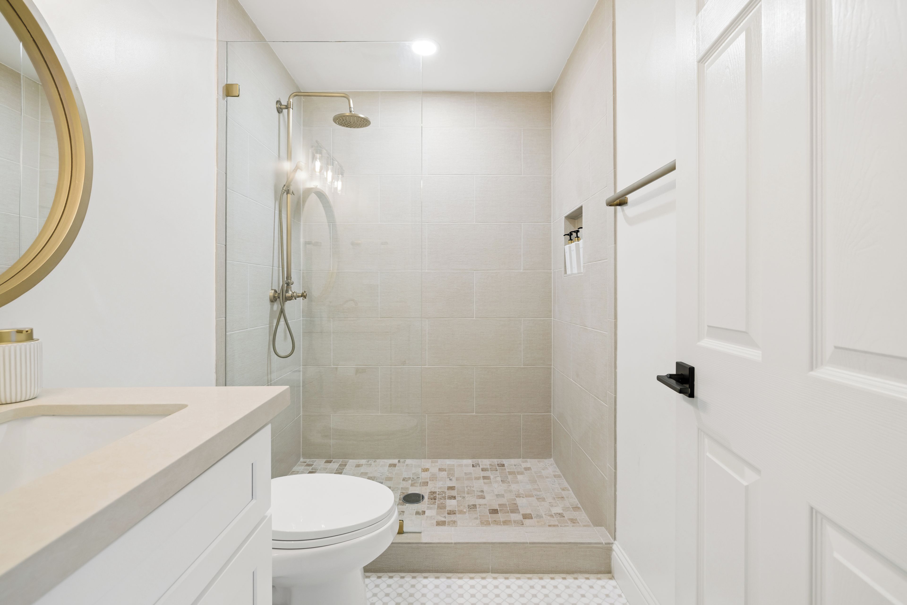 Un baño con inodoro, ducha con puerta de cristal y lavabo con espejo.