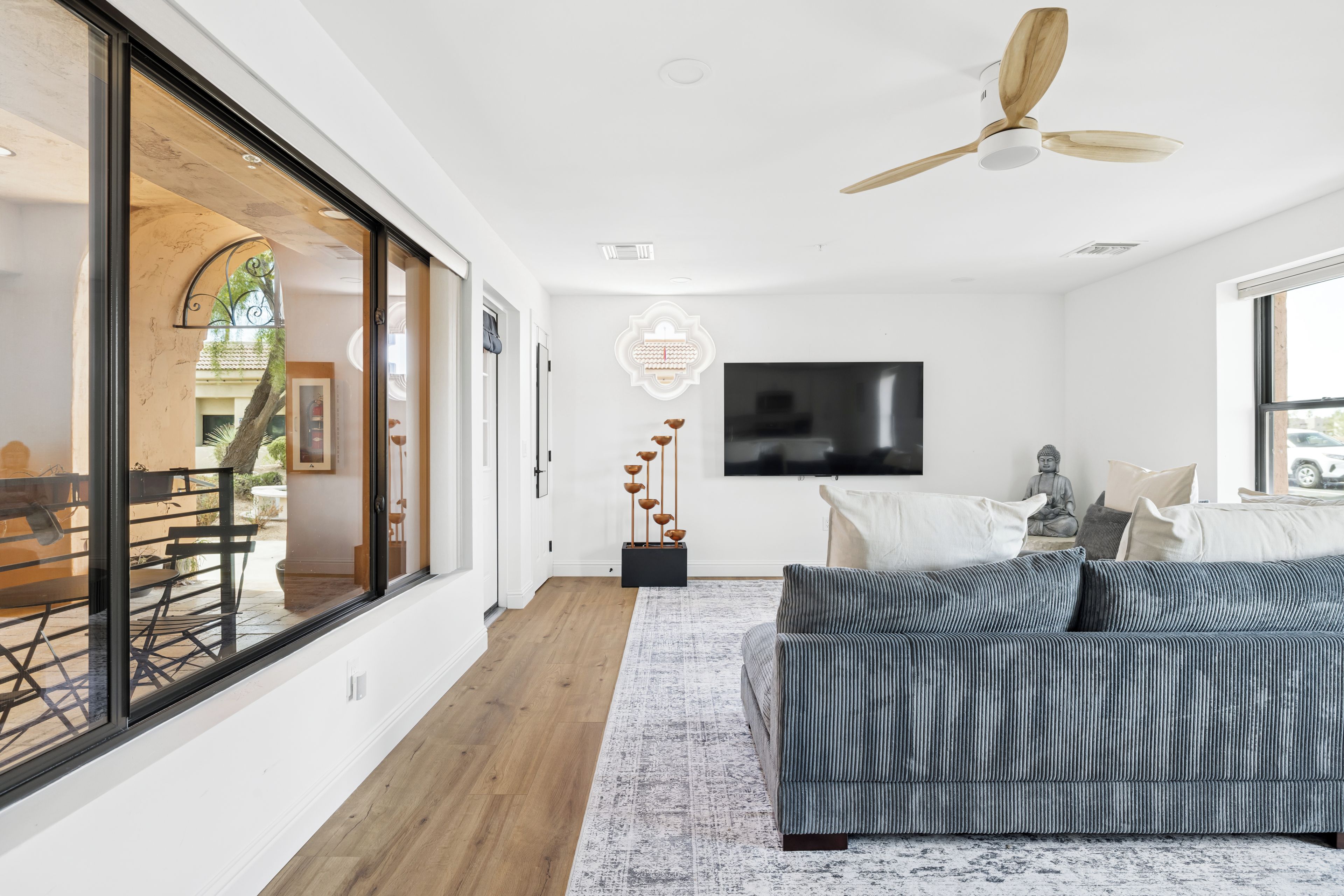 A modern living room with a sofa, a television, and a ceiling fan.