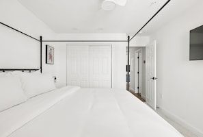 A bedroom with a bed, a door, and a wall-mounted light fixture.