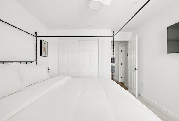 Un dormitorio con cama, una puerta y una lámpara fijada a la pared.