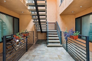 Un escalier avec une rampe en métal, bordé de plantes en pot et agrémenté d’un banc.
