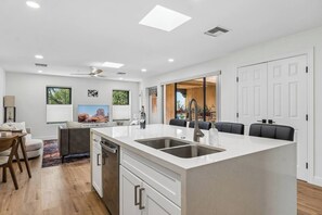 Una cocina moderna con una isla central, electrodomésticos integrados y un comedor con sofá y sillas.