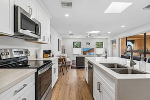 A modern kitchen with a central island, built-in appliances, and a dining area with a view.
