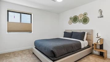Un dormitorio con cama, ventana con persianas, ventilador de techo y decoración en la pared.