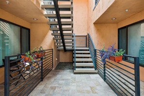 A staircase with a metal railing, flanked by potted plants and a bench.