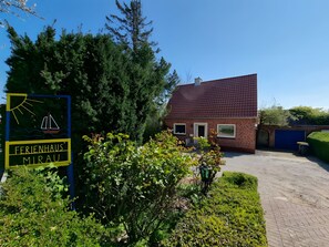 A brick building with a red roof, a sign with a sailboat, and a well-maintained garden.