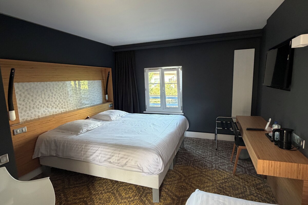 Een hotelkamer met een groot bed, een bureau, een stoel en een televisie.
