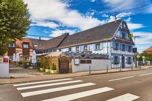 Een klassiek vakwerkhuis met een puntdak, een hekpoort en een straatbeeld met een zebrapad.