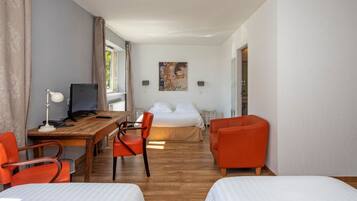 Une chambre d’hôtel avec un lit, un bureau avec un ordinateur, deux chaises et un tableau au mur.