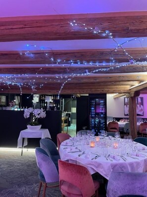Een terras met eettafels, slingers en een bar op de achtergrond.