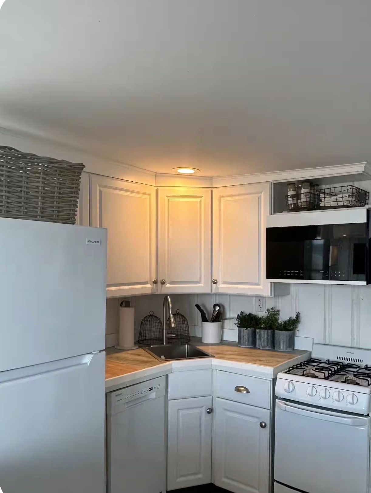 A kitchen with white cabinetry, a stainless steel sink, a gas stove, and a microwave.