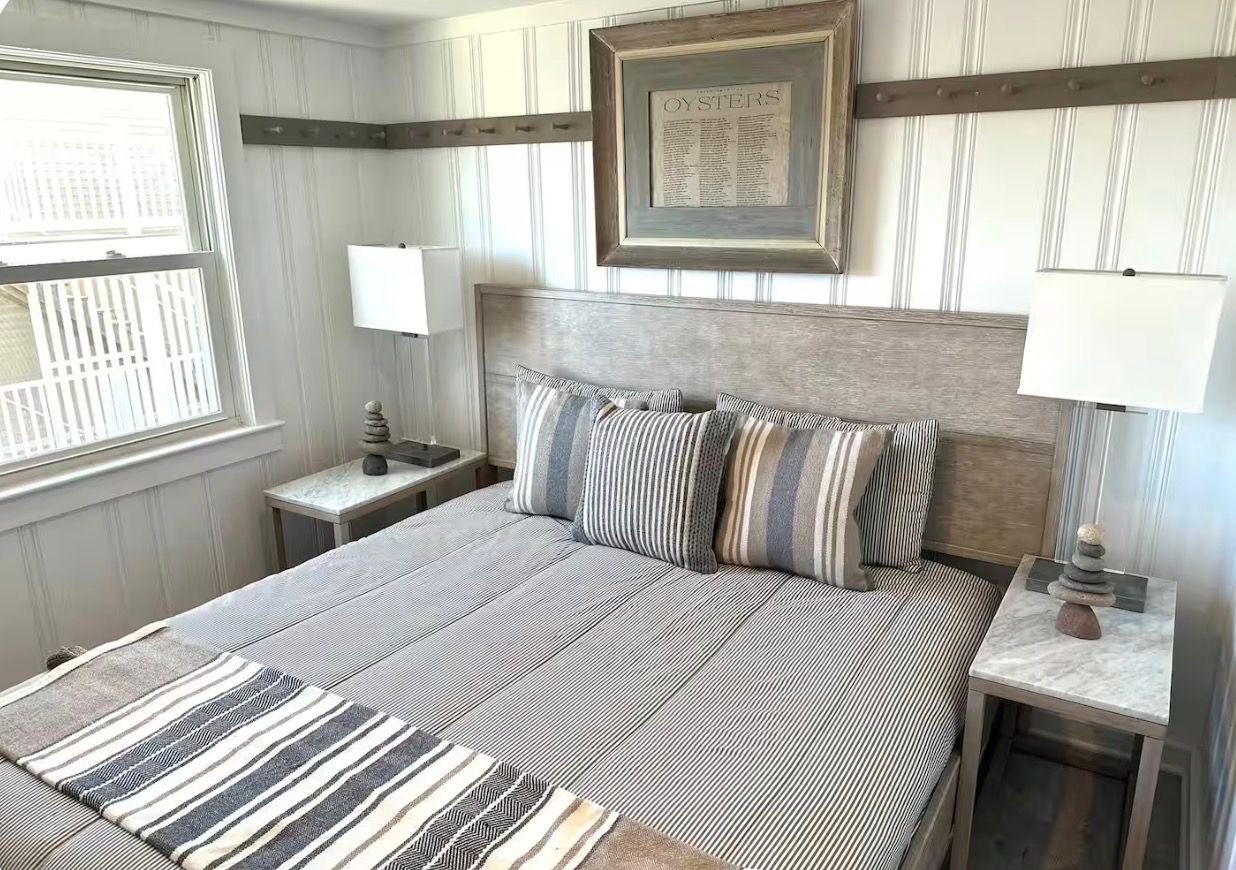 A neatly arranged bedroom with a bed, two bedside tables, a lamp, and a framed picture on the wall.