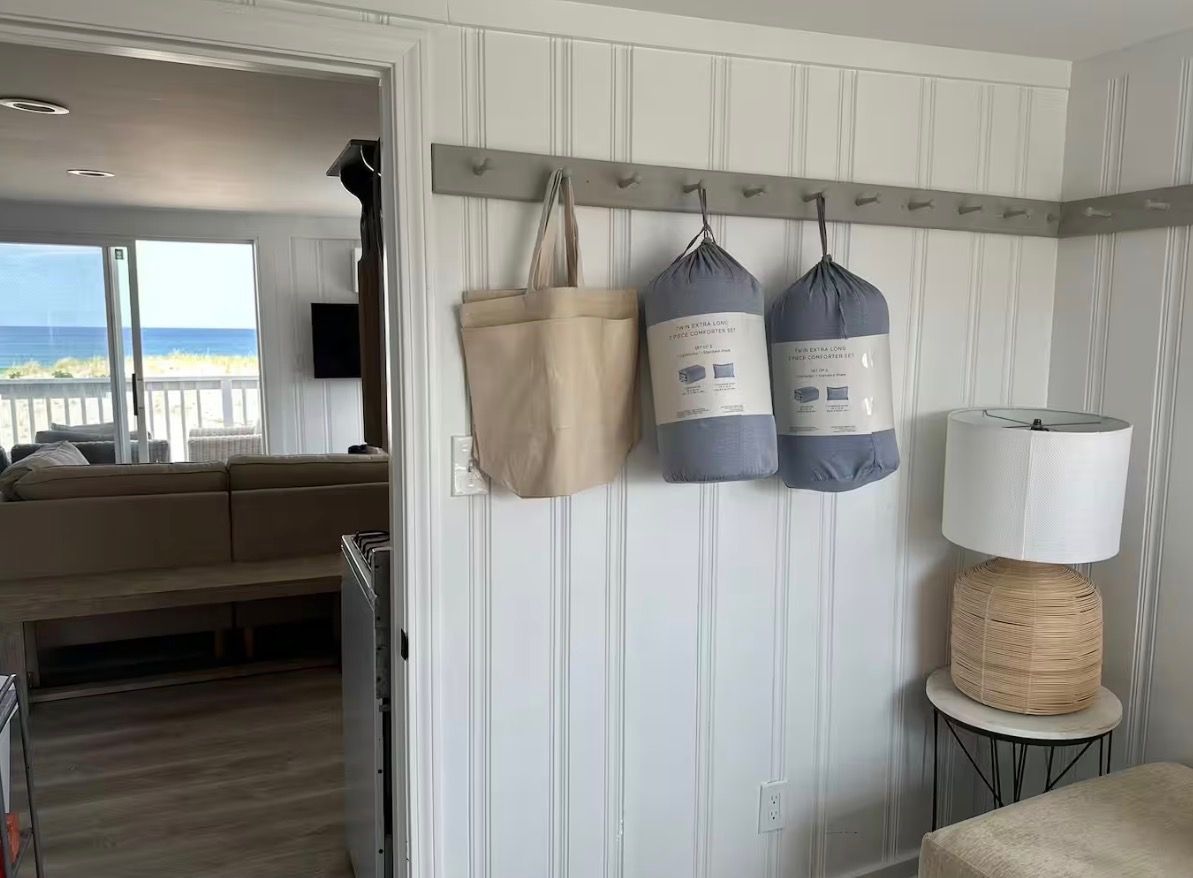 A room with a sofa, a lamp, and a wall-mounted coat rack with bags.