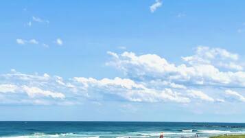 A beach with people, a clear sky, and the ocean.