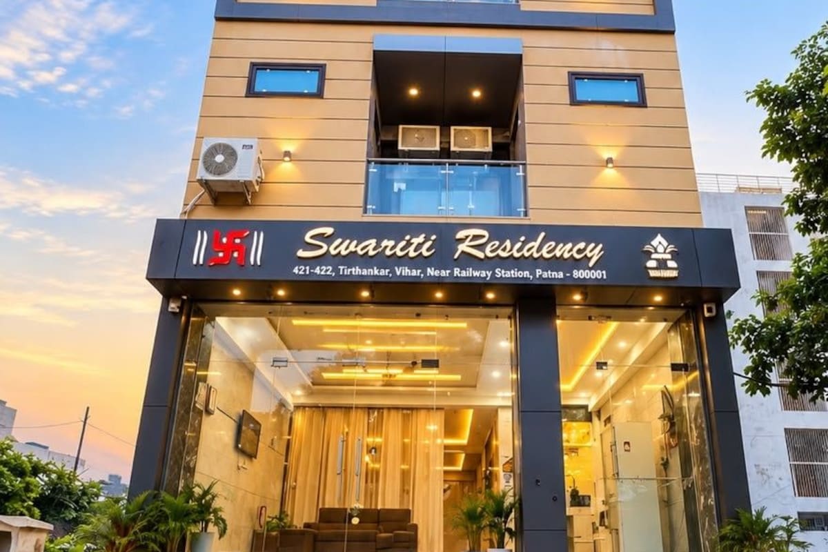 A modern building with a sign for Swaridhi Residency. It has multiple floors, balconies, and a well-lit entrance.