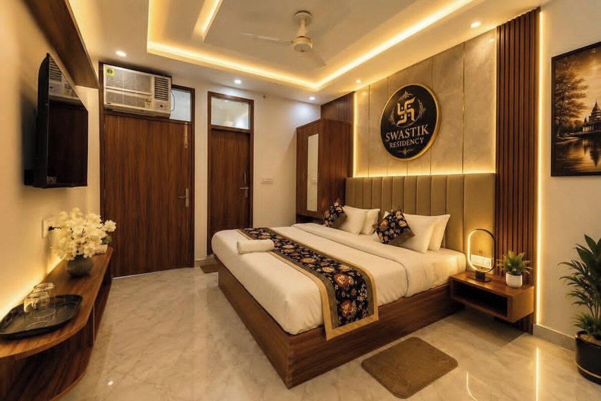 Un dormitorio moderno con cama, mesitas de noche, televisor en la pared y ventilador de techo.
