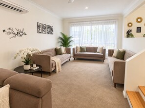 A living room with two sofas, a coffee table, and a potted plant. - Cosy Sunlit home with a Pool (Smithfield)