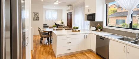 A modern kitchen with a central island, built-in appliances, and a large window with a view.