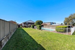 A residential property with a well-maintained lawn, a swimming pool, and a fenced backyard. - Cosy Sunlit home with a Pool (Smithfield)
